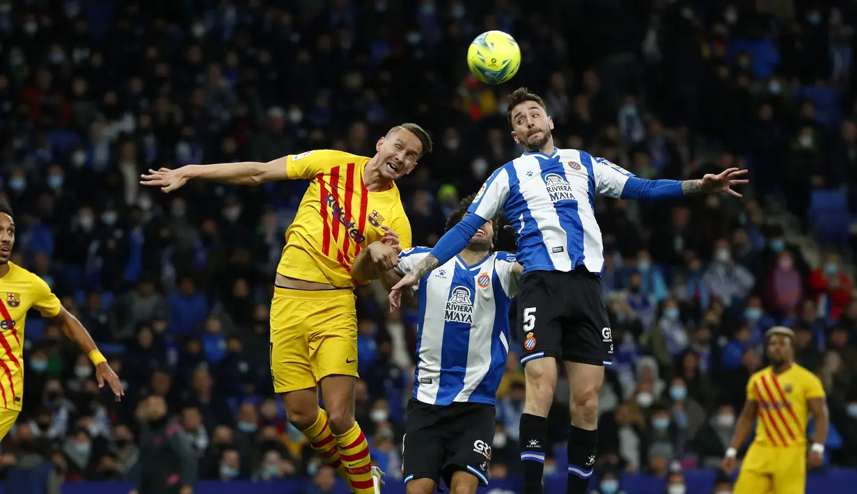 Penyerang Barcelona Luuk de Jong melompat saat berebut bola dengan bek Espanyol Fernando Calero pada jornada ke-24 Liga Spanyol 2021/22 di RCDE Stadium, Senin dini hari WIB (14/2/2022). Espanyol dan Barcelona bermain imbang 2-2. (AP Photo/Joan Monfort)