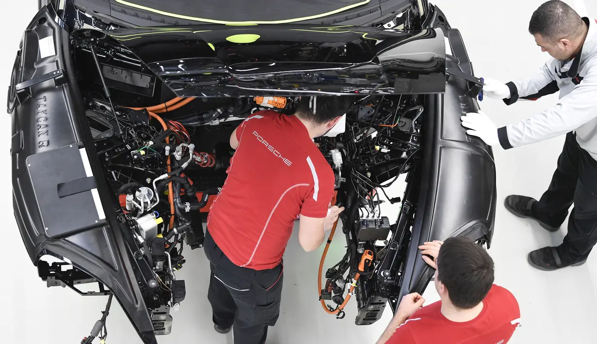 Mekanik melakukan pemasangan instalasi listrik mobil Porsche Taycan saat proses perakitan di pabrik perusahaan Porsche AG di Stuttgart, Jerman, Rabu (4/3/2020). Porsche Taycan merupakan mobil bertenaga listrik pertama  dari pembuat mobil mewah Jerman, Porsche AG. (AFP Photo/Thomas Kienzie)