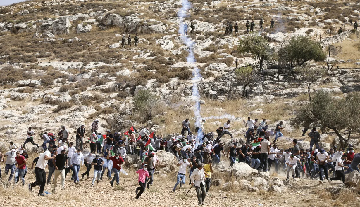 Pengunjuk rasa Palestina menghindari gas air mata yang ditembakkan tentara Israel saat memprotes pencaplokan tanah untuk perluasan permukiman Yahudi di dekat desa Beit Dajan, timur Nablus, Palestina (9/10/2020). (AFP/Jaafar Ashtiyeh)