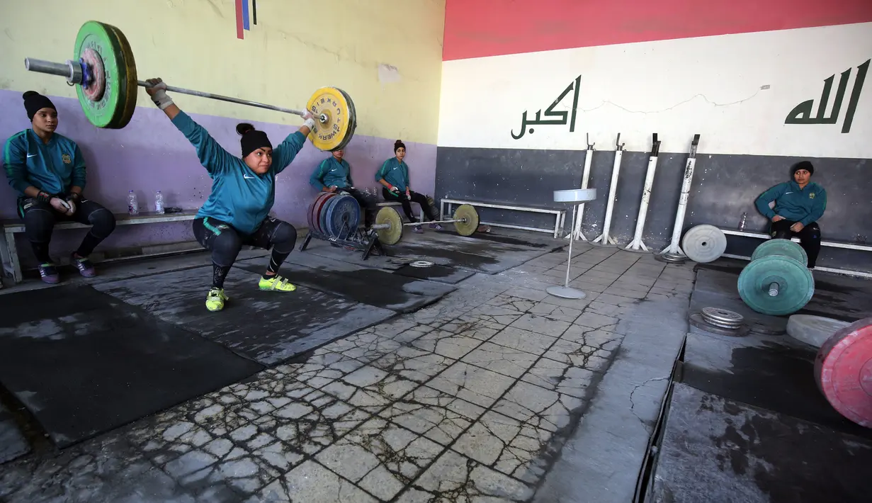 Atlet angkat besi wanita Irak Huda Salim Al-Saedi mengangkat beban saat berlatih di sebuah klub di Kota Sadr, sebelah timur Baghdad, Irak (18/1). (AFP Photo/Ahmad Al-Rubaye)