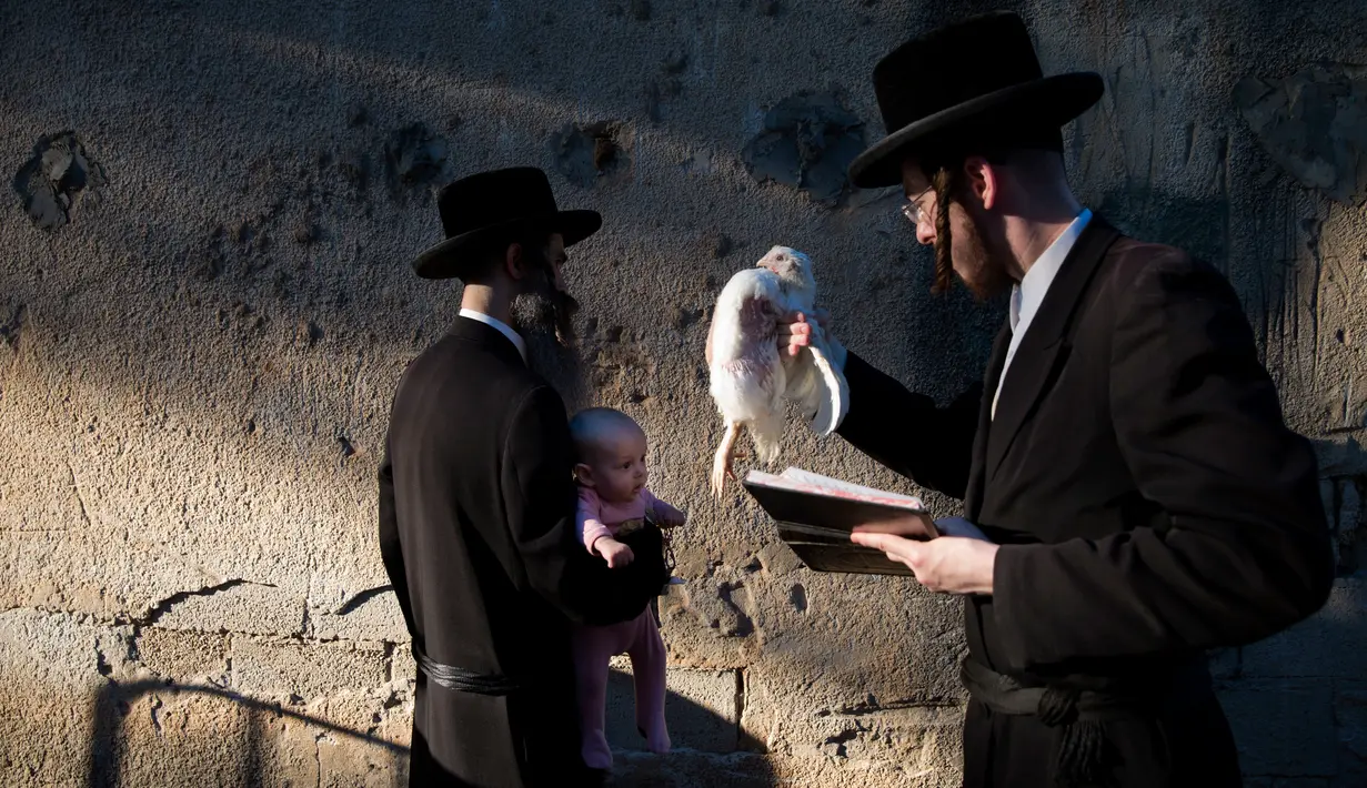 Pria Yahudi ultra-Ortodoks mengayunkan ayam memutari kepala bayi dalam ritual Kaparot di Bnei Brak, Israel, Minggu (16/9). Tradisi yang dimulai 800 tahun lalu itu digelar sebelum perayaan Yom Kippur atau Hari Penebusan pada Selasa esok. (AP/Oded Balilty)