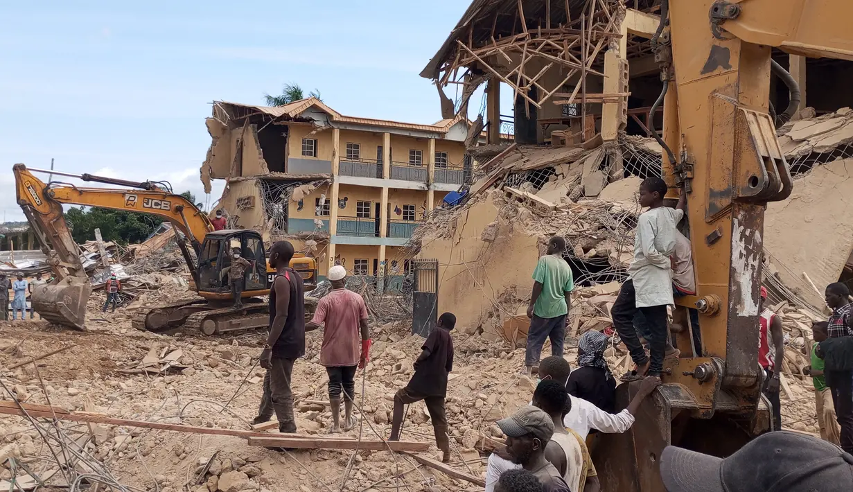 Petugas penyelamat menggunakan alat berat di lokasi sekolah yang sebelumnya runtuh, sementara warga berkumpul untuk mengamati upaya penyelamatan di distrik Jos North di Negara Bagian Plateau, Nigeria, Jumat (12/7/2024). (Muhammad Tanko Shittu / AFP)