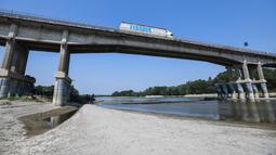Kendaraan melintasi jembatan di atas dasar sungai Po yang mengering di Boretto, timur laut Parma, pada Rabu (15/6/2022). Menurut pengamat sungai, kekeringan yang mempengaruhi sungai terbesar di Italia, Po adalah yang terburuk dalam 70 tahun terakhir. (Piero CRUCIATTI / AFP)