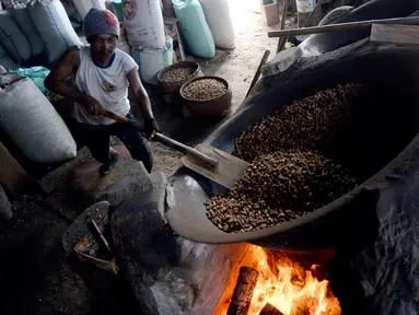 Pekerja mengolah kacang dengan media pasir di salah satu industri rumahan pembuatan kacang sangrai di Kawasan Keranggan, Tangerang Selatan, Selasa (11/8/2020). Kacang sangrai yang dipasarkan seharga Rp10.000 per kg itu mulai mengalami kenaikan pesanan dibanding bulan lalu. (merdeka.com/Dwi Narwoko)