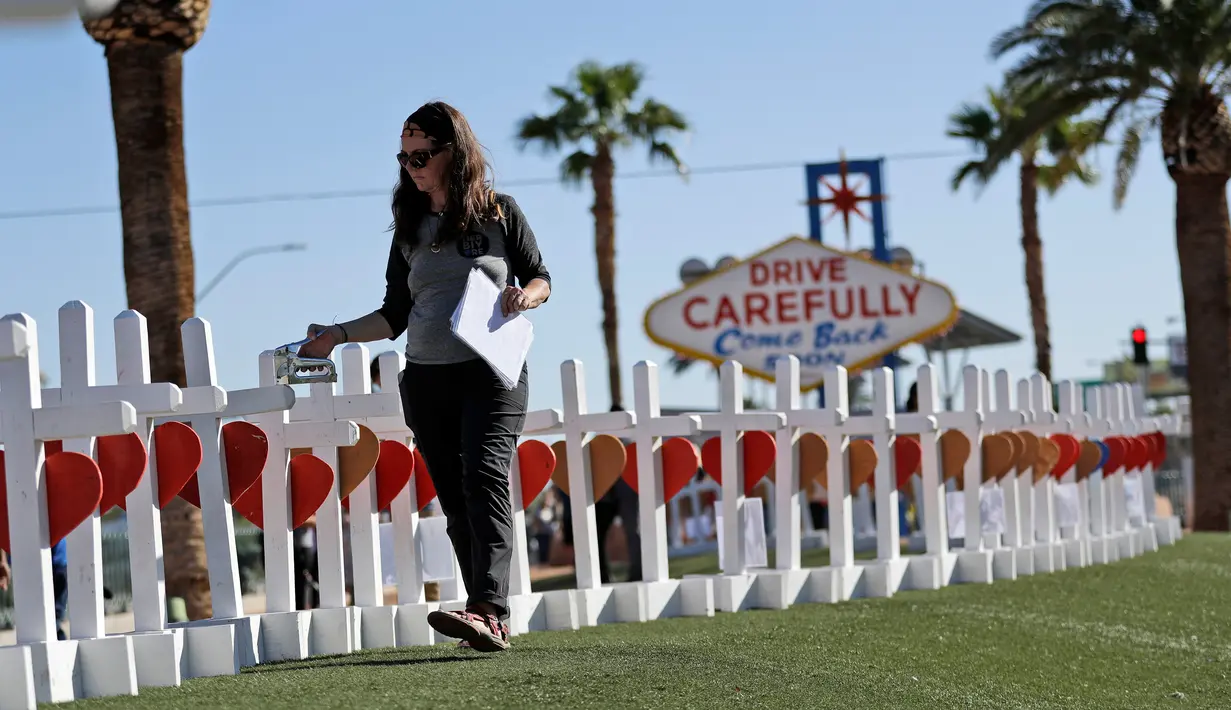 Sherri Camperchioli menata nisan untuk menghormati korban tewas penembakan massal yang terjadi dekat Kasino Mandalay Bay di Las Vegas, Jumat (6/10). Sebanyak 58 nisan kayu berbentuk salib itu ditambahkan ornamen hati berwarna merah. (AP/Gregory Bull)