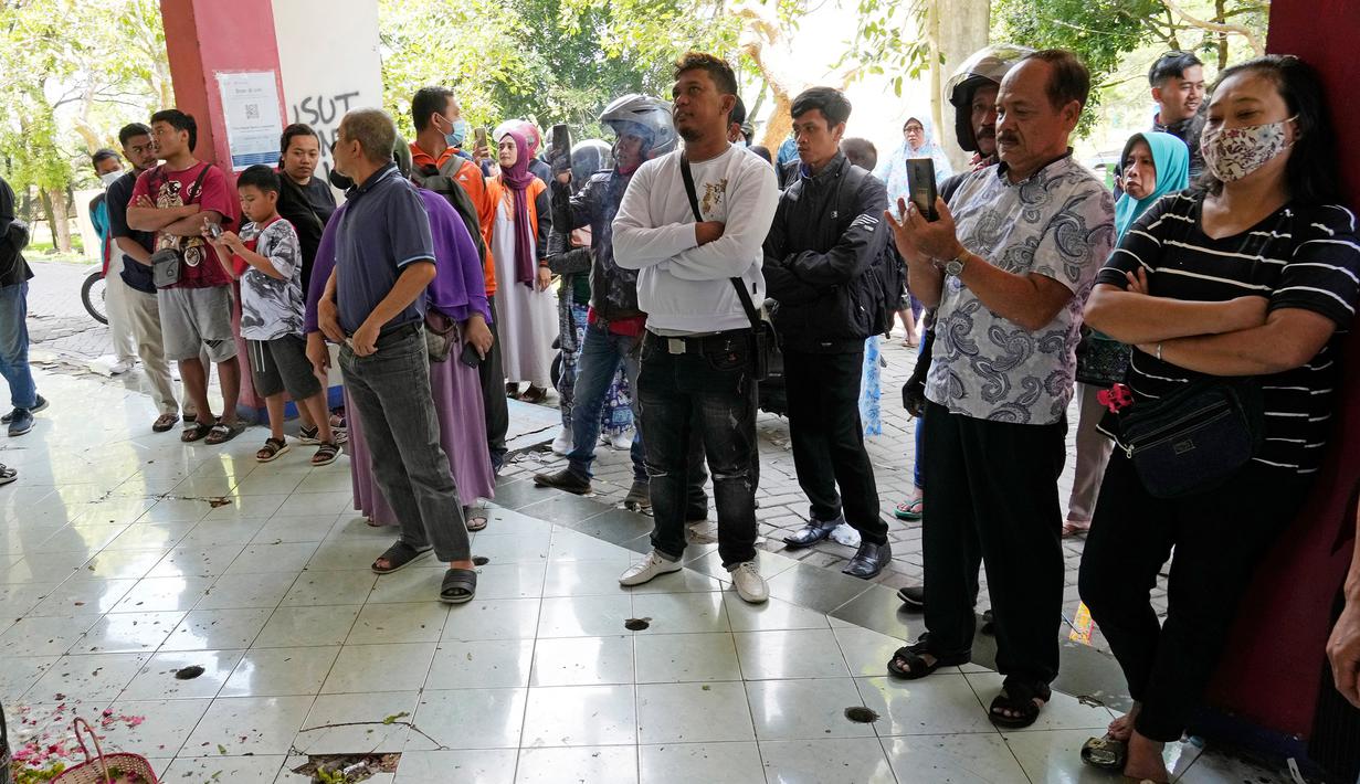 Orang-orang berdiri di tugu peringatan darurat untuk korban kerusuhan di depan Gerbang 13, Stadion Kanjuruhan, Malang, Selasa (4/10/2022). Polri menjatuhkan sanksi kepada 10 anggota polisi dan menyelidiki 18 orang lainnya buntut tragedi kerusuhan yang menewaskan 125 orang di Stadion Kanjuruhan. (AP Photo/Achmad Ibrahim)