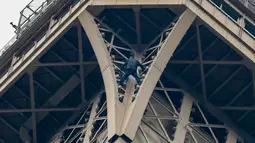 Seorang pria tak dikenal nekat memanjat Menara Eiffel tanpa peralatan keselamatan di Paris, Senin (20/5/2019). Tim pemadam kebakaran termasuk seorang spesialis pendakian berada di lokasi dan menghadapi penyusup itu yang motivasinya masih belum diketahui. (FRANCOIS GUILLOT / AFP)