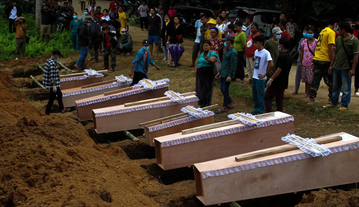 Orang-orang membawa peti mati saat pemakaman massal berlangsung untuk menguburkan korban dugaan serangan militer di sebuah kamp pengungsi dekat Kota Laiza, Myanmar, Selasa (10/10/2023). Sebanyak 29 orang tewas dan puluhan lainnya luka-luka dalam serangan yang diduga dilakukan oleh militer di sebuah kamp pengungsi di Myanmar utara, kata juru bicara kelompok pemberontak etnis yang menguasai wilayah tersebut kepada AFP pada 10 Oktober. (STR/AFP)