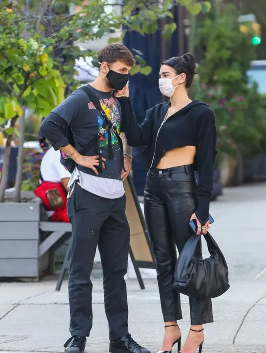 Terlihat sedang bersama sang kekasih Anwar Hadid, Dua Lipa kembali mengenakan outfit serba hitam. Sweater edgy yang asimetris dipadunya dengan celana kulit berwarna hitam dan heels hitam, dan kembali menenteng Bottega Veneta Shoulder Pouch. Foto: Document/Bottega Veneta.