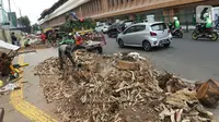Sejumlah pekerja memotong sisa tebangan pohon di trotoar kawasan Cikini, Jakarta, Selasa (5/11/2019). Dinas Kehutanan DKI Jakarta menebang pohon di seberang Stasiun Cikini dan akan mengganti pohon angsana dengan yang tidak merusak konstruksi pedestrian. (Liputan6.com/Herman Zakharia)