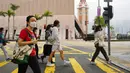 Orang-orang yang memakai masker berjalan di sepanjang jalan di Hong Kong, Jumat (28/1/2022). Hong Kong memangkas masa karantina wajib bagi orang-orang yang datang dari luar negeri dari 21 menjadi 14 hari. (AP Photo/Kin Cheung)