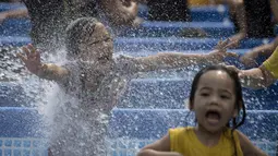 Ekspresi anak-anak saat bermain di kolam portabel yang diberikan oleh pemerintah setempat mendinginkan tubuh pada saat musim panas di Manila, Filipina (12/4). (AFP Photo/Noel Celis)