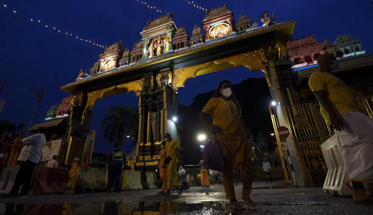 Umat Hindu yang mengenakan masker memasuki pintu masuk kuil Sri Subramaniyar selama festival Thaipusam karena umat mematuhi prosedur operasi standar yang ketat karena pandemi COVID-19 di Gua Batu di pinggiran Kuala Lumpur, Malaysia, Selasa (18/1/2022). (AP Photo/ Vincent Thian)