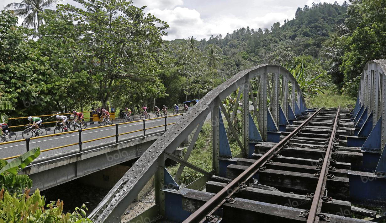 Pebalap melewati rel kereta yang terbengkalai yang dibangun tahun 1914 pada Etape 6 dari Padang Pariaman menuju Sawahlunto, Sumatera Barat, Kamis (11/8/2016). (Bola.com/Nicklas Hanoatubun)