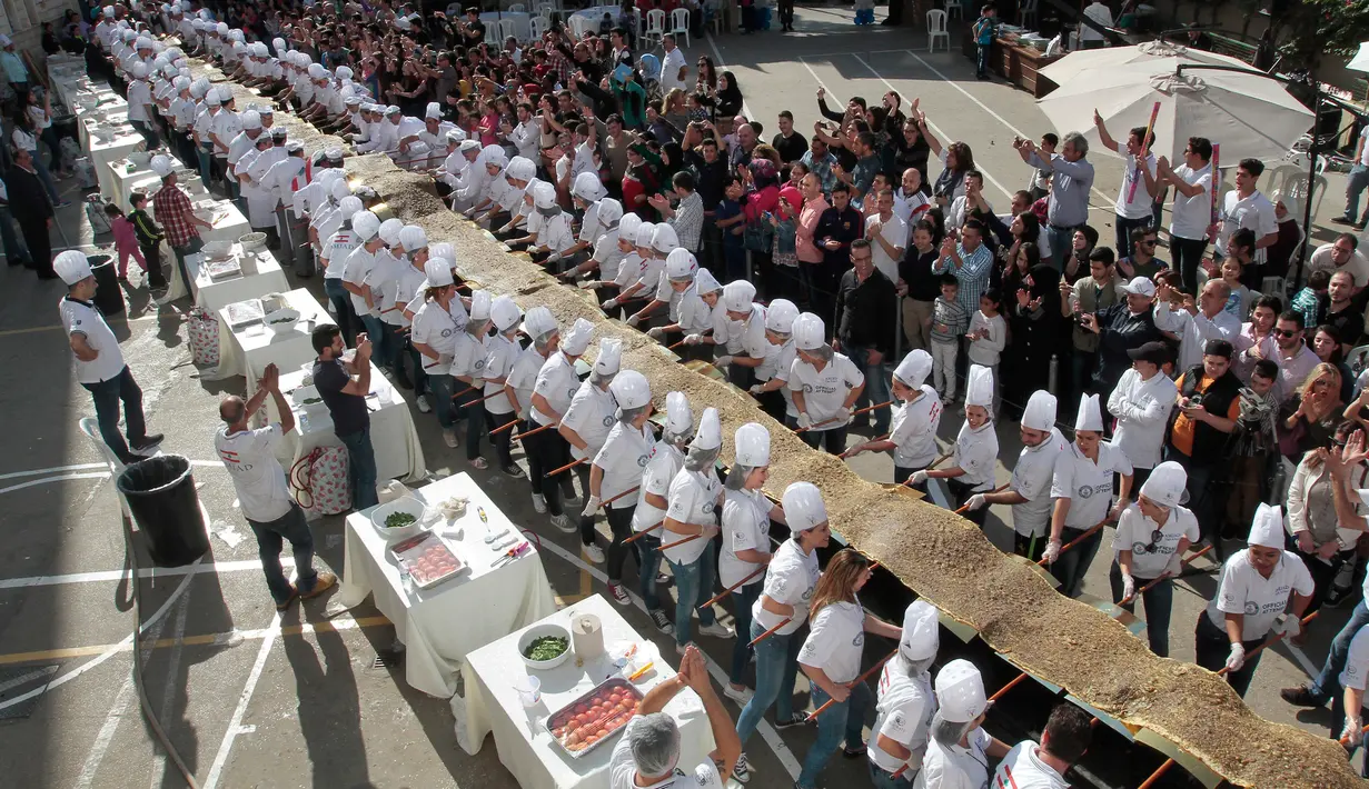 Peserta menyiapkan roti manousheh dengan rempah-rempah, wijen dan minyak zaitun, di Choueifat, Beirut, Lebanon (22/11). Roti sepanjang 32 meter ini disiapkan untuk memperingati Hari Kemerdekaan Lebanon dengan tujuan memecahkan rekor dunia. (AFP PHOTO/STR)