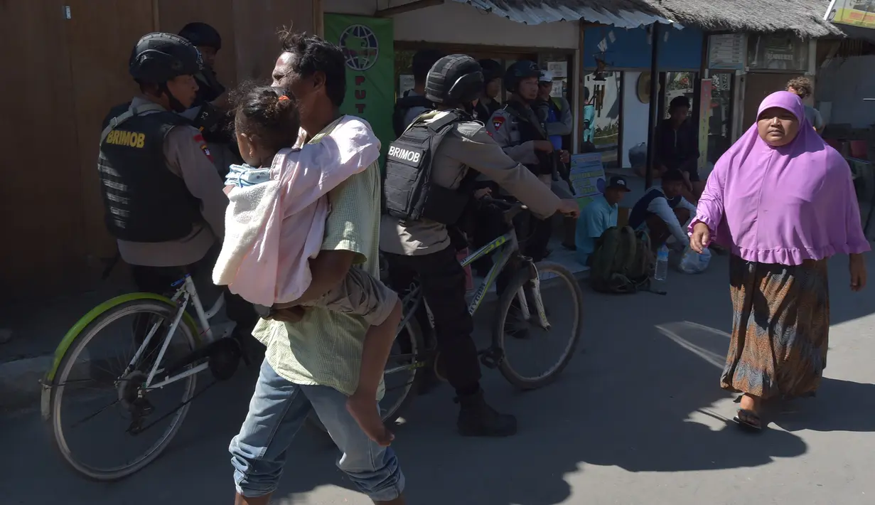 Masyarakat lalu lalang saat polisi bersepeda berpatroli di kawasan wisata Pulau Gili Air, Lombok, Nusa Tenggara Barat (NTB), Sabtu (11/8). Patroli dilakukan setelah gempa 7 skala Richter melanda Lombok pada 5 Agustus lalu. (Adek BERRY/AFP)