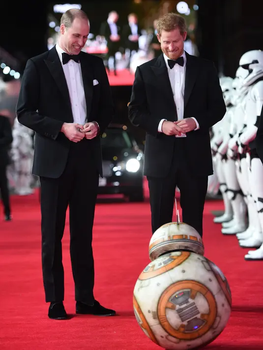 Pangeran William dan Pangeran Harry melihat robot droid BB-8 ketika berjalan di karpet merah premiere film The Star Wars: The Last Jedi yang digelar di The Royal Albert Hall, London, Inggris, Selasa (12/12). (Eddie Mulholland/Pool Photo via AP)