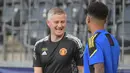 Pelatih Manchester United, Ole Gunnar Solskjaer (kiri) berbincang dengan penyerang Jadon Sancho (kanan) dalam sesi latihan di Bern (13/9/2021). Manchester United akan bertanding melawan Young Boys pada Grup F Liga Champions di Stadion Wankdorf. (AFP/Sebastien Bozon)