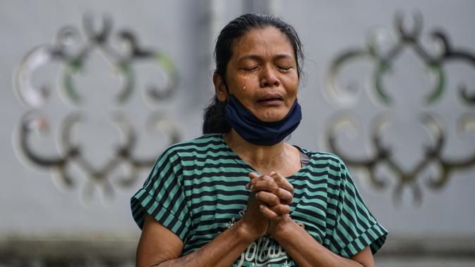 Seorang perempuan berdoa saat peringatan 16 tahun gempa bumi dan tsunami Aceh di sebuah kuburan massal di Siron, Sabtu (26/12/2020).  Peringatan di tengah pandemi COVID-19 itu tetap berlangsung secara sederhana melalui kegiatan ziarah kubur. (CHAIDEER MAHYUDDIN/AFP)
