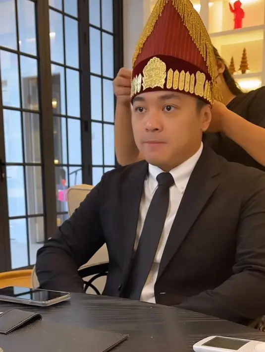 Sementara Cas mengenakan setelan jas hitam, lengkap dengan kemeja dan dasi hitam. Tak ketinggalan, tali-tali atau topi Batak dan sortali dikenakan di kepalanya. [@riantic/@__rose_makeupartist/@meli_makeuphairdowedding]