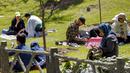 Orang-orang duduk di sebuah taman saat warga Iran berpiknik di luar rumah bersama keluarga dan teman untuk menandai "Sizdeh Bedar" (Hari Alam), 13 hari setelah tahun baru Nowruz Persia, di utara Teheran, Minggu (2/4/2023). (Photo by AFP)