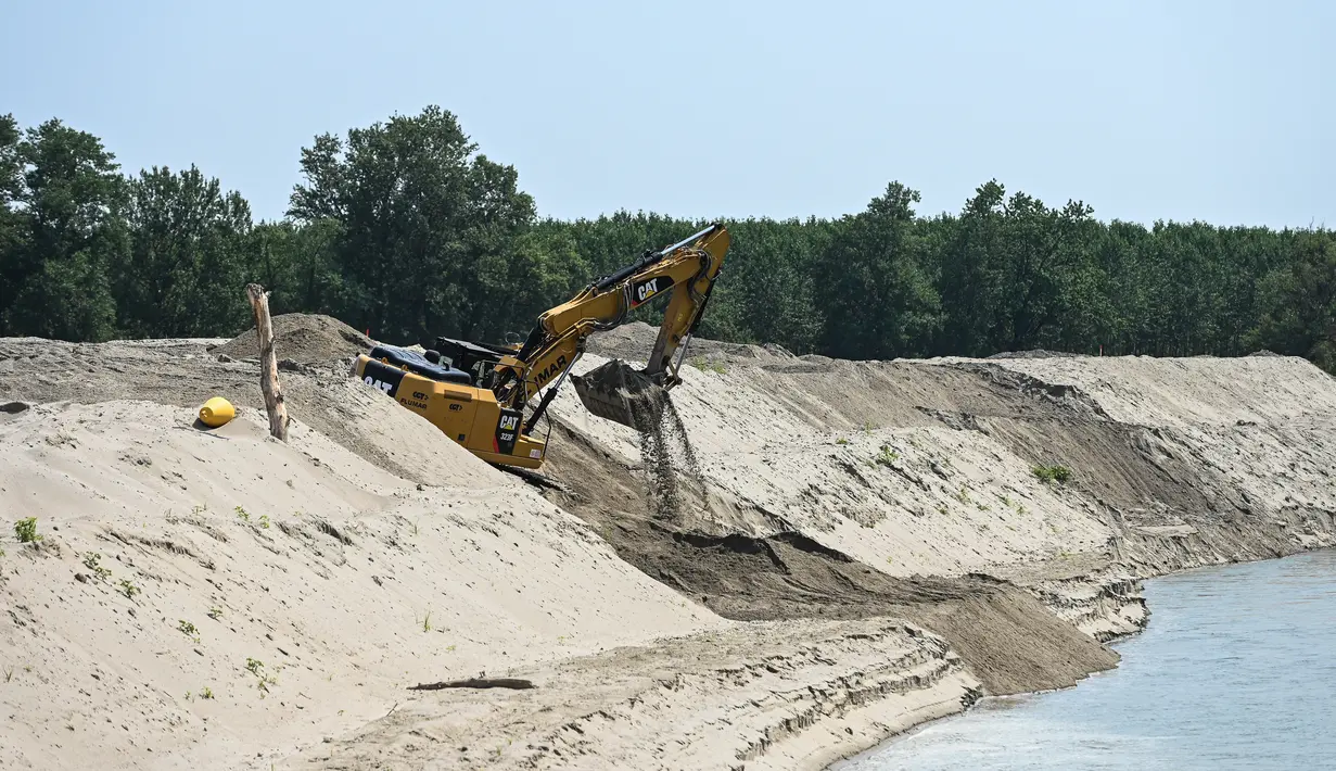 <p>Ekskavator bekerja untuk menurunkan tingkat dasar sungai dan memungkinkan air mencapai pompa hidrolik yang menyediakan air untuk sistem irigasi daerah sungai Po di Boretto, timur laut Parma, Rabu (15/6/2022). Menurut pengamat sungai, kekeringan yang mempengaruhi sungai terbesar di Italia, Po adalah yang terburuk dalam 70 tahun terakhir. (Piero CRUCIATTI / AFP)</p>