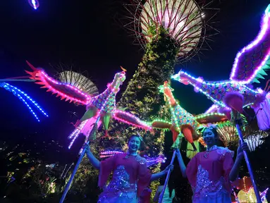 Dua orang wanita dari rombongan Tian Eng Dragon and Lion Dance Centre tampil membawakan tarian phoenix yang dihiasi dengan lampu warna-warni di Gardens by the Bay, Singapura (4/2). (AFP/Roslan Rahman)