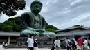 Orang-orang mengenakan masker saat mengunjungi The Great Buddha atau yang biasa disebut Kamakura Daibutsu di kuil Kotoku-in di Kamakura, Prefektur Kanagawa, Jepang, Sabtu (20/6/2020). Patung Buddha dari perunggu yang menjulang dengan tinggi 13,35 meter ini didirikan tahun 1252. (Behrouz MEHRI/AFP)