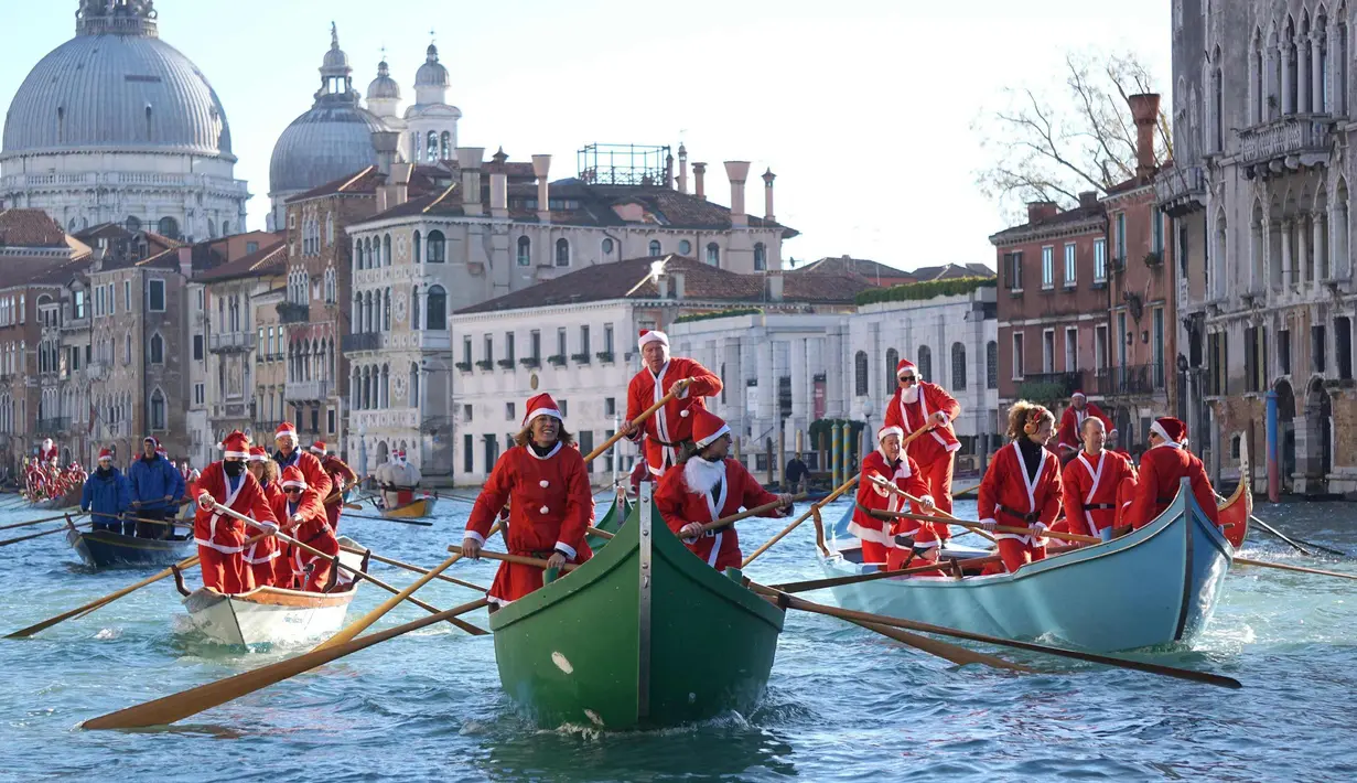 Ratusan orang mengenakan kostum Santa Claus mendayung perahu berparade di sepanjang Canal Grande di Venesia, Italia, (17/12). Sekitar dua ratus pendayung memberikan kehidupan pada prosesi air tradisional Santa Claus. (Andrea Merola / ANSA via AP)