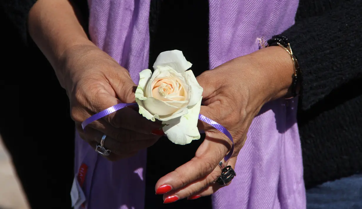 Seorang wanita memegang bunga mawar saat melakukan aksi jelang jelang Hari Penghapusan Kekerasan Perempuan Internasional di pemakaman Juarez, Negara Bagian Chihuahua, Meksiko, (24/11). (AFP Photo/Herika Martinez)