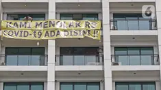Penghuni Nine Residence memasang spanduk penolakan RS darurat COVID-19 di Lippo Plaza Mampang, Jakarta, Minggu (5/4/2020). Mereka keberatan dan menolak pembangunan dan pengoperasian RS pasien COVID-19 di sebagian Lippo Plaza Mampang yang ada dalam satu kawasan. (Liputan6.com/Herman Zakharia)