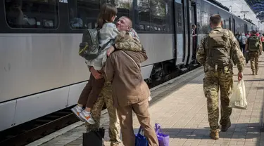 Seorang prajurit Ukraina memeluk istri dan putrinya di stasiun kereta api di Sloviansk, wilayah Donetsk, Ukraina pada Selasa, 12 September 2023. (AP Photo/Hanna Arhirova)