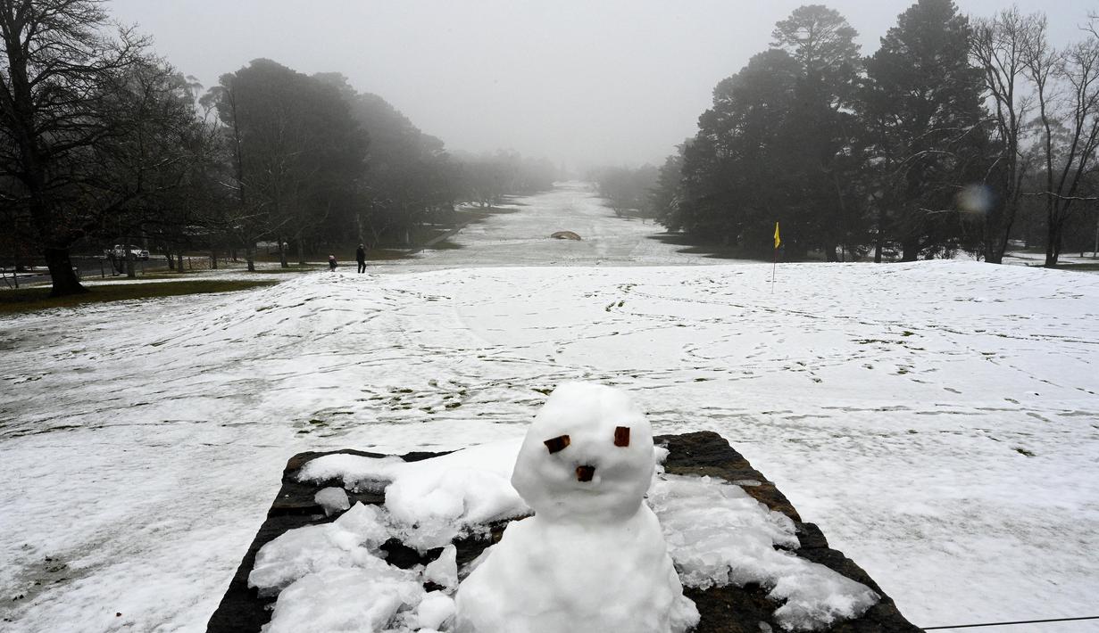 Anak-anak bermain (kiri) di dalam lapangan golf yang tertutup salju pertama musim ini di Katoomba di Blue Mountains (10/6/2021). (AFP/Saeed KHAN)
