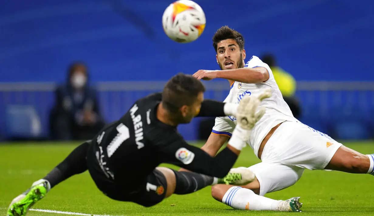 Penyerang Real Madrid Marco Asensio menendang bola melewati kiper Mallorca Manolo Reina untuk mencetak gol pada jornada keenam La Liga Spanyol di Santiago Bernabeu, Kamis (23/9/2021) dini hari WIB. Real Madrid berpesta gol usai melibas Real Mallorca 6-1. (AP Photo/Manu Fernandez)