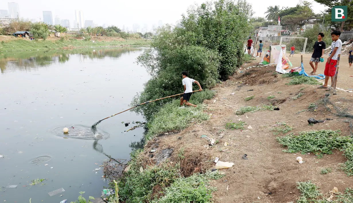 Seorang anak berusaha mengambil bola yang terjatuh ke kali Banjir Kanal Barat (BKB), Jakarta. Menjamurnya pemukiman dan gedung-gedung pencakar langit di Jakarta yang begitu cepat mengakibatkan lahan bermain anak menjadi korbannya. (bola.com/M Iqbal Ichsan)