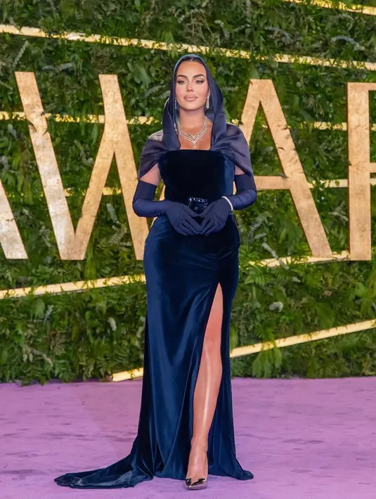 Dengan percaya diri, Georgina kenakan tube suede dress dan gloves di Arab Saudi. Kenakan kain organza sebagai kerudung, outfit Georgina memamerkan tubuh bagian atas [@georginagio]