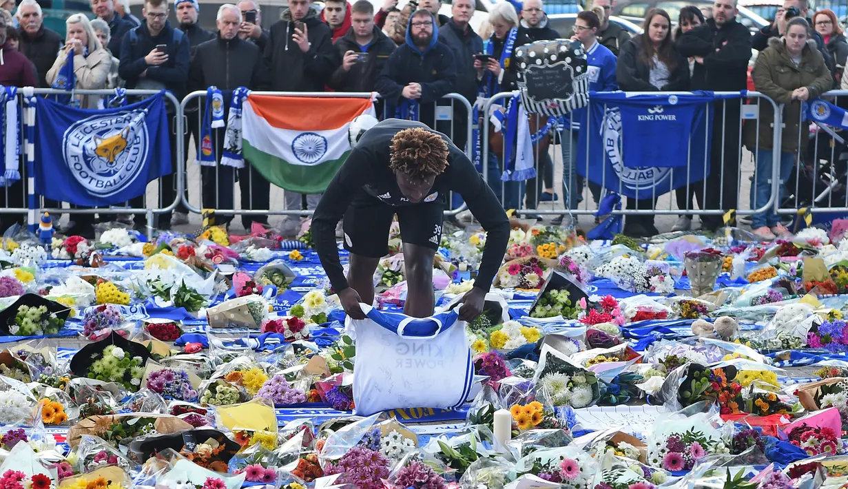 Pemain Leicester City, Darnell Johnson memberi penghormatan kepada korban kecelakaan helikopter yang menewaskan pemilik Leicester City Vichai Srivaddhanaprabha di luar Stadion King Power, Inggris, Senin (29/10). (Paul Ellis/AFP)
