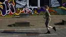 Seorang anak laki-laki melewati grafiti di hari musim semi yang hangat di Amsterdam, Belanda, Selasa (30/3/2021). Kasus COVID-19 di Belanda telah menembus satu juta lebih. (AP Photo/Peter Dejong)