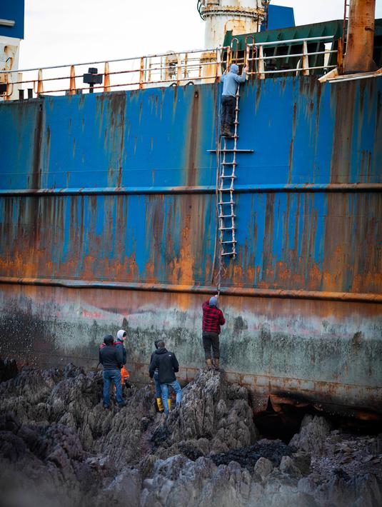 Warga menaiki kapal kargo sepanjang 77 meter, MV Alta, yang terjebak di atas batu di dekat Ballycotton, Cork, Selasa (18/2/2020). "Kapal hantu" yang berlayar tanpa awak selama lebih dari satu tahun hanyut dan terbawa ke pantai selatan Irlandia menyusul sapuan Badai Dennis. (Cathal Noonan/AFP)