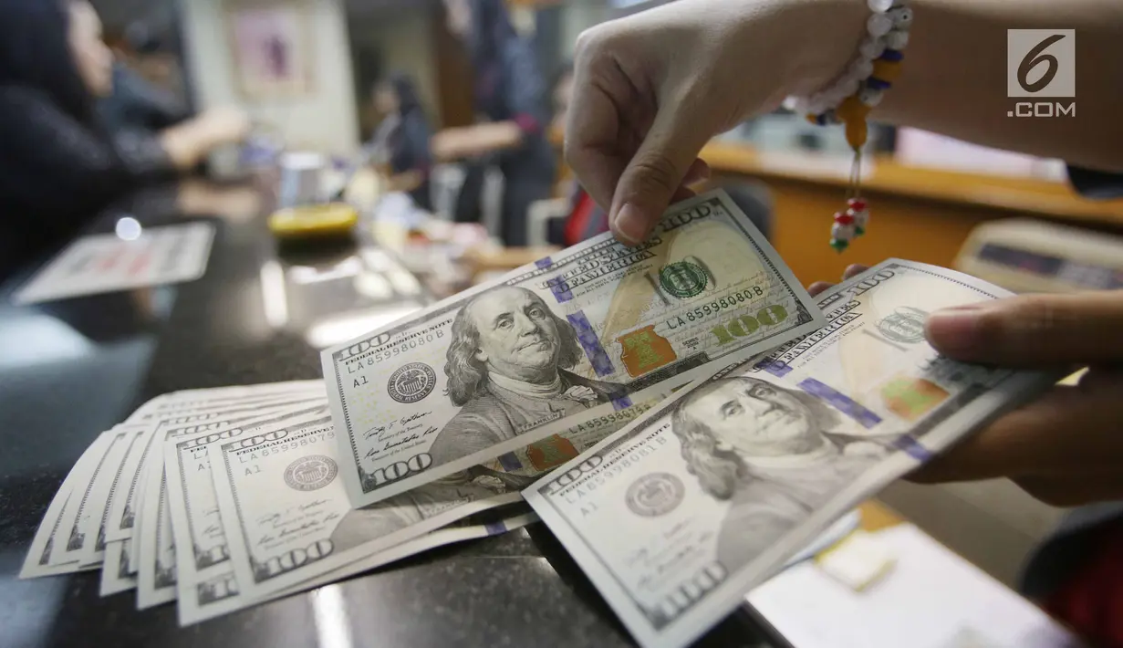 Teller menghitung mata uang dolar di Jakarta, Jumat (2/2). Dengan nilai tersebut posisi nilai tukar rupiah sudah masuk level undervalued, atau telah keluar dari level fundamentalnya. (Liputan6.com/Angga Yuniar)
