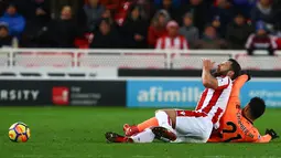 Bek Stoke City, Erik Pieters berebut bola dengan gelandang Liverpool, Alex Oxlade-Chamberlain pada pekan ke-14 Premier League di Bet365 Stadium, Kamis (30/11). Liverpool berhasil membantai Stoke City dengan skor 3-0. (Geoff CADDICK/AFP)