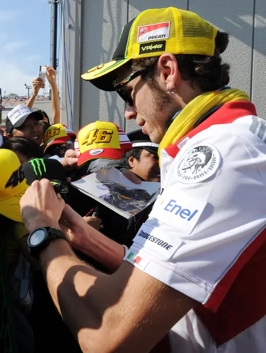 Sebuah tanda tangan sangat berarti bagi penggemar Valentino Rossi, pembalap ini pun tak pelit untuk sekedar berbagi tanda tangan karena dukungan mereka sangat penting baginya. (AFP/Bintang.com)
