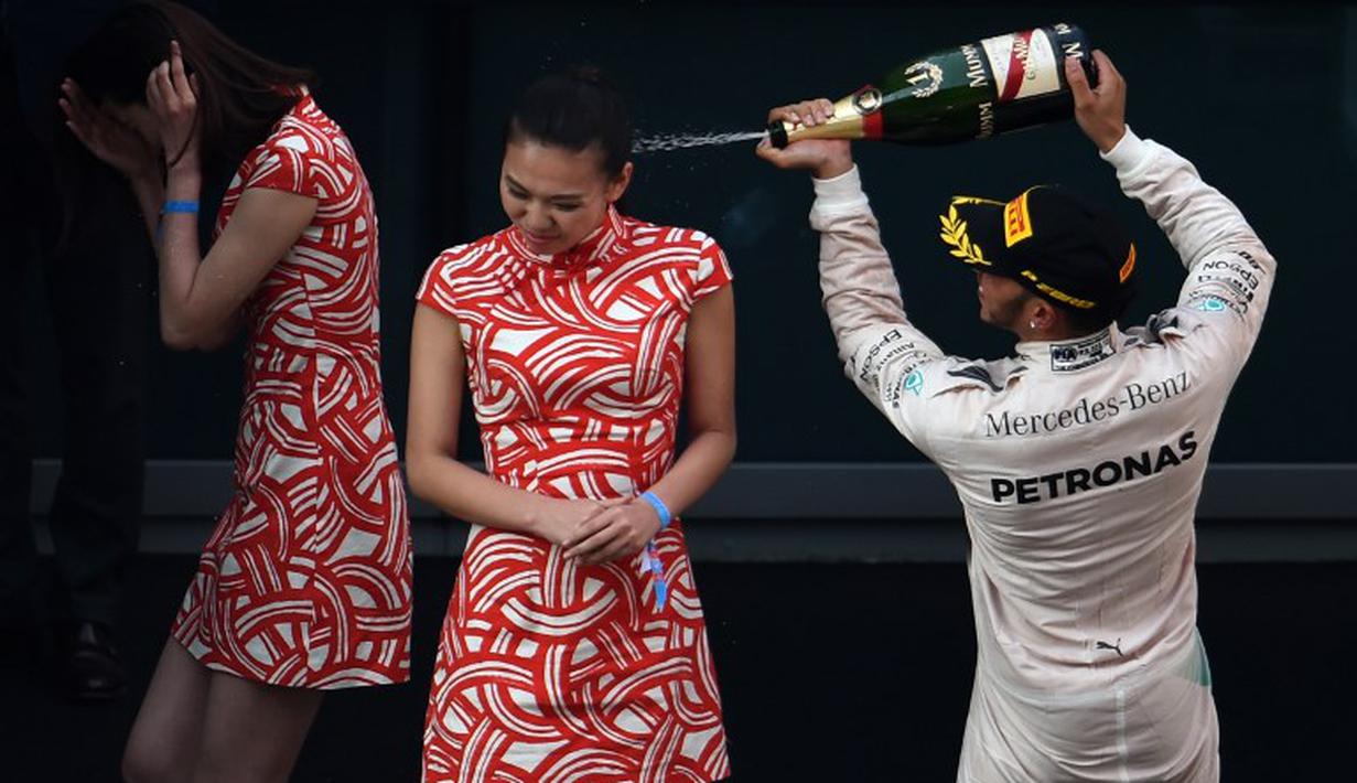 Lewis Hamilton menyemprotkan sampanye ke arah gadis podium.