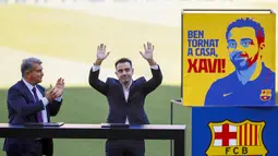 Pelatih baru Barcelona Xavi Hernandez (kanan) melambai ke penonton di sebelah presiden Barcelona Joan Laporta selama presentasi resminya di stadion Camp Nou, Spanyol, Senin (8/11/2021). Xavi dikontrak selama dua tahun sampai Juni 2023 mendatang. (AP Photo/Joan Monfort)