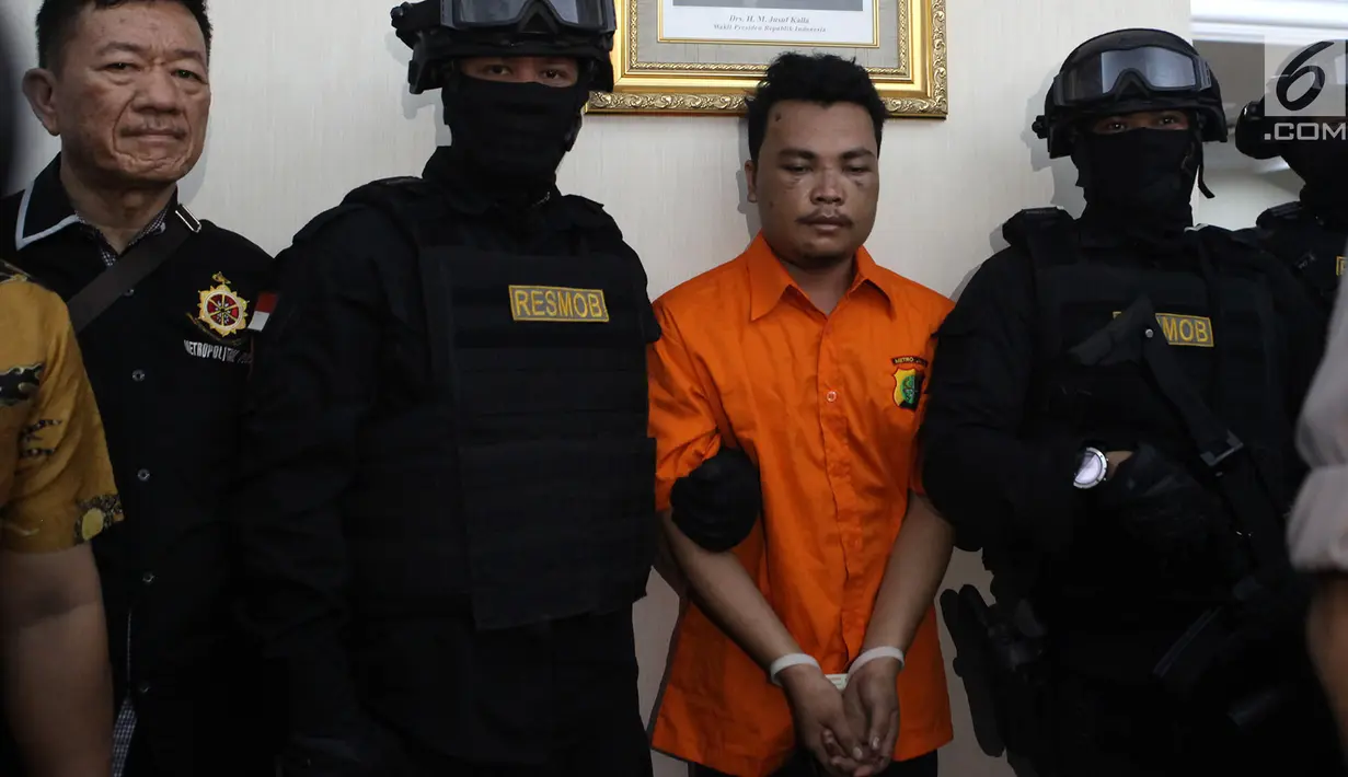 Polisi mengawal tersangka pembunuhan satu keluarga di Kota Bekasi saat gelar perkara di Polda Metro Jaya, Jakarta, Jumat (16/11). Polisi mengungkapkan tersangka HS membunuh keluarga Diperum Nainggolan seorang diri. (Merdeka.com/Imam Buhori)