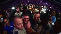 Khabib Nurmagomedov tengah diamankan oleh petugas keamanan menuju kamar ganti usai bertarung melawan Conor McGregor (Harry How/AFP)