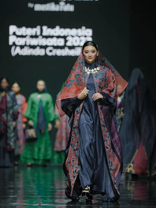 Adinda Cresheilla mengenakan dress tunik biru dengan aksen outer batik. Adinda lengkapi outfitnya dengan kerudung yang serupa dengan outernya [@officialputeriindonesia]