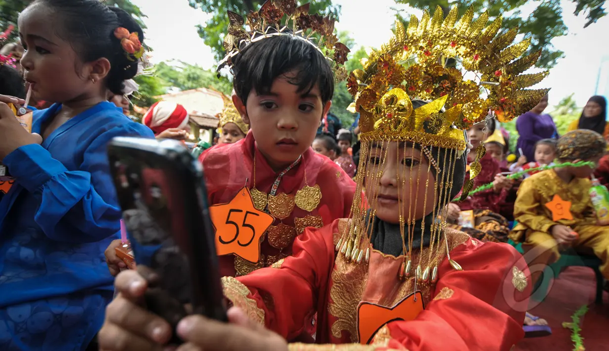 Murid TK Sekolah Alternatif untuk Anak Jalanan (SAAJA) ber-selfie dengan mengenakan pakaian adat di kawasan Kuningan, Jakarta, Selasa (21/4/2015). Kegiatan tersebut dalam rangka Hari Kartini yang diperingati setiap 21 April. (Liputan6.com/Faizal Fanani)