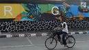 Seorang pria bersepeda melintas di depan mural bertema Asian Games 2018 di kawasan Universitas Negeri Jakarta, Kamis (16/8). Mural karya mahasiswa seni rupa tersebut dibuat dalam rangka menyambut Asian Games 2018. (Liputan6.com/Immanuel Antonius)