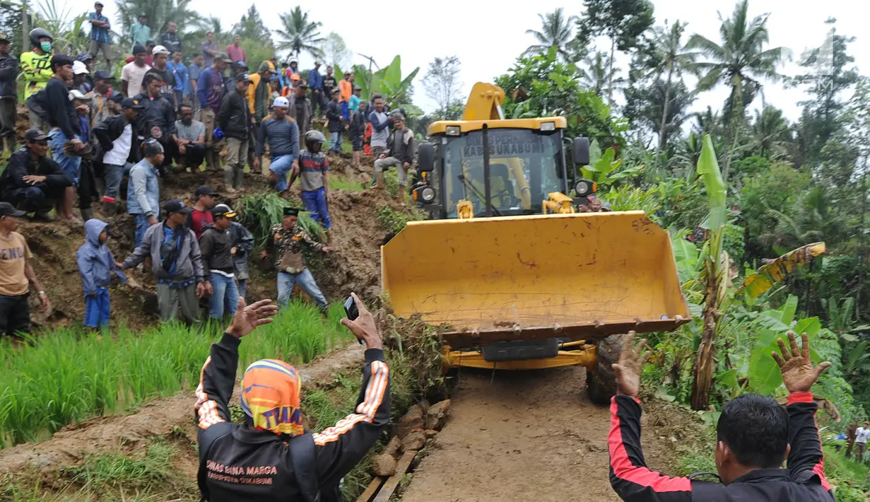 Warga memandu alat berat melalui jalan kecil menuju lokasi longsor di Dusun Cimapag, Sirnaresmi, Cisolok, Sukabumi, Jawa Barat, Selasa (1/1). Sebanyak 38 warga belum ditemukan dan masih dalam proses pencarian. (Merdeka.com/Arie Basuki)
